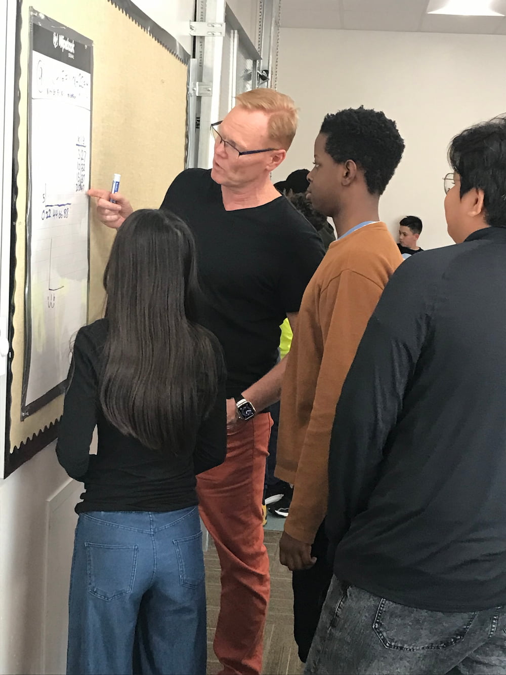 Students collaborating at vertical whiteboards in a Building Thinking Classrooms math class